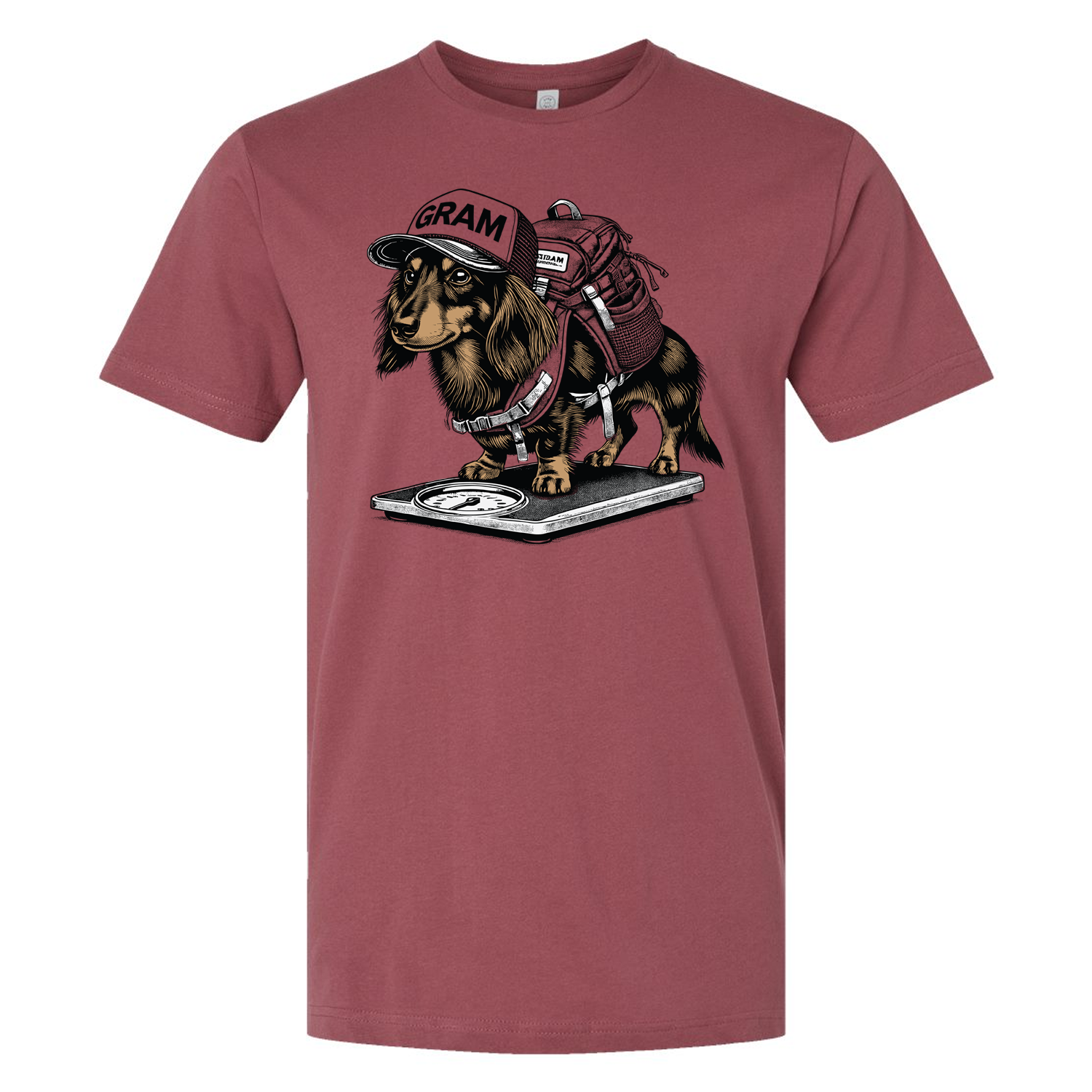 Graphic T-shirt featuring a cartoon Dachshund dog wearing a backpack and hat that says "GRAM" while standing on a bathroom scale. Funny ultralight backpacking or gram weenie apparel.